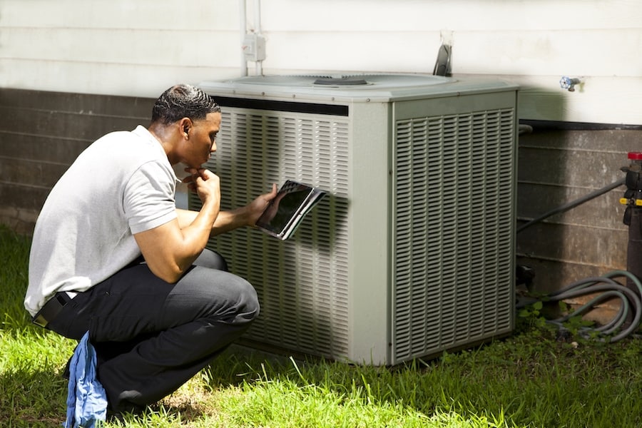 HVAC technician inspecting an air conditioning unit outside in Owensboro, KY.