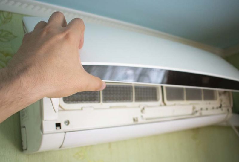 hand open the lid of the air conditioner in the room