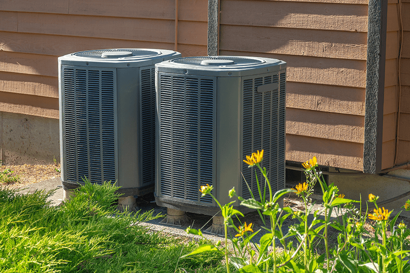 Two air conditioning units outside of a home.