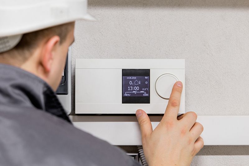 Image of technician working with thermostat. Why Schedule Air Conditioning Maintenance?